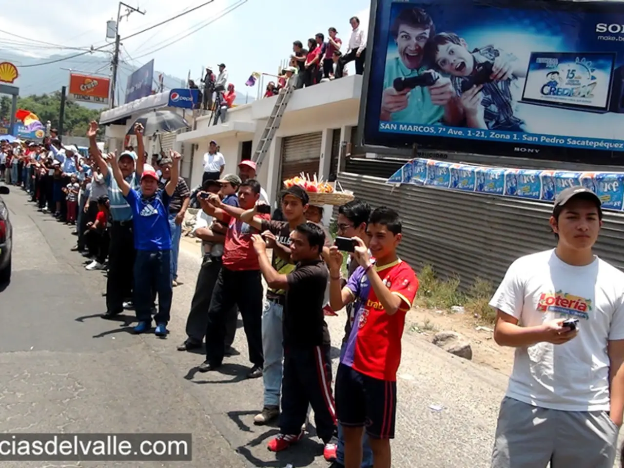 In the center of the image there is a road on which there are people standing. There are vehicles....