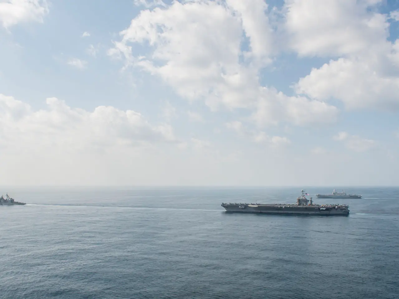 3 Ships are moving in this water. At the top it's a cloudy sky.