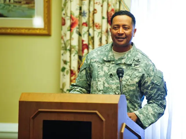 In the foreground of this image, there is a man standing in front of a podium on which there is a...