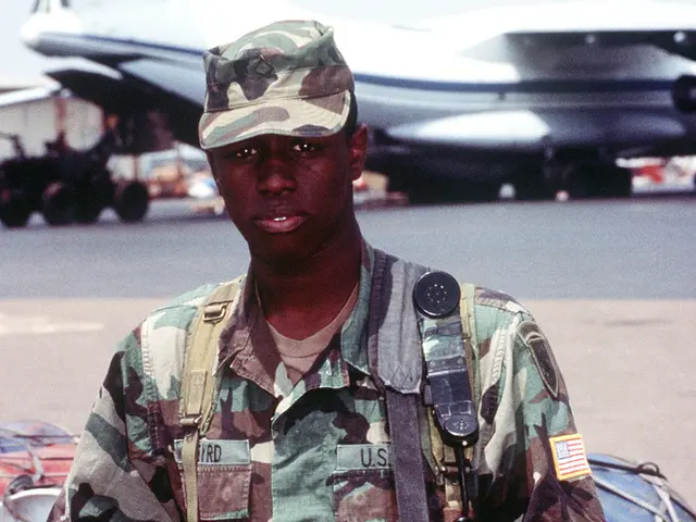 In this image we can see a soldier holding a gun and standing and we can see some objects behind...