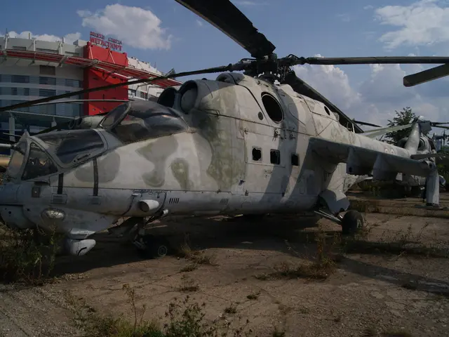 In the center of the image there is a chopper. In the background of the image there is building. At...