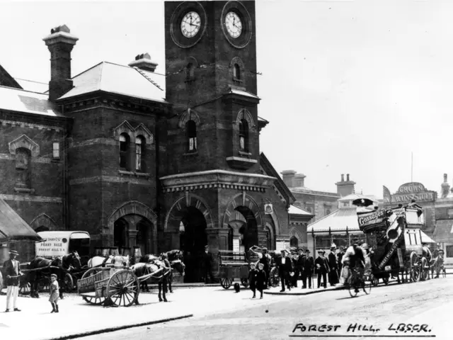 It is a black and white picture, this is a building, in the left side there are horse carts and in...