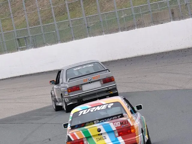 Here we can see two cars on the road. In the background there are poles on a platform, fence and...