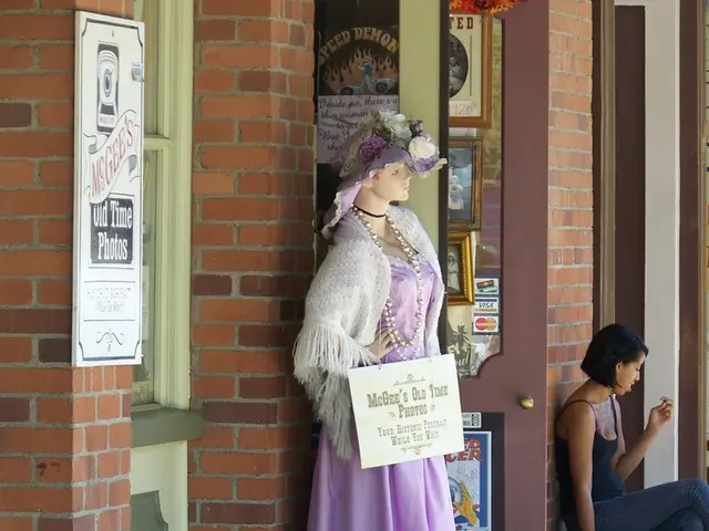 In this picture there is a mannequin wearing purple color dress, standing out side the shop. Behind...