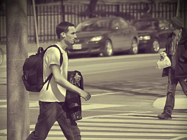 In this image, I can see two people walking on the road. I can see two cars, which are parked. This...