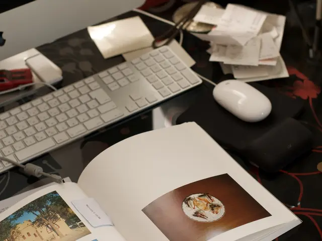 This picture shows a monitor and a keyboard and we see a book and few papers and a mouse on the...