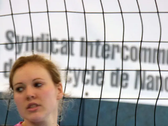 In the image there is a woman in the foreground and behind her there is some net.