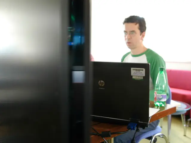 A man is sitting in the chair and looking into the laptop.