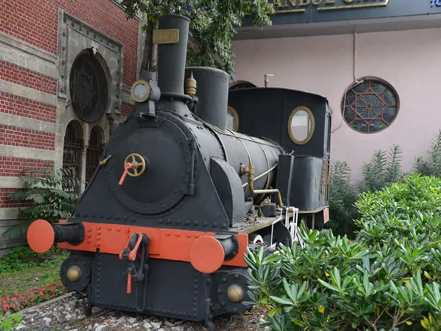 In the middle it's a toy rail engine in black color. On the left side there is a brick wall, on the...