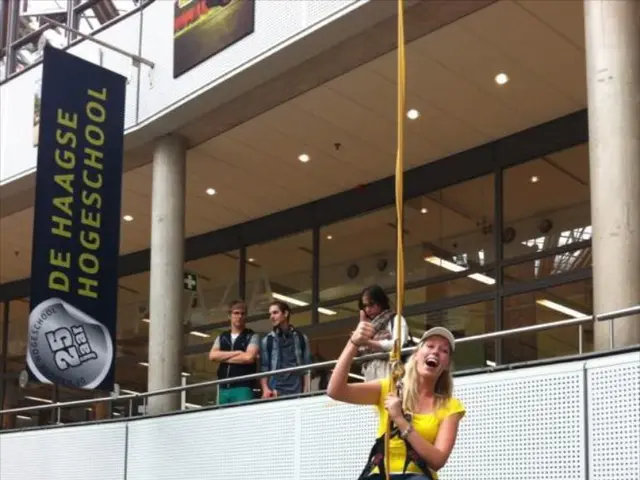 In this image we can see a woman wearing yellow T-shirt, cap and red color boots is hanged to the...