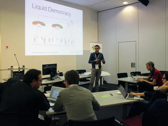 This picture is clicked in a conference hall. Here, we see five people sitting on chair and...