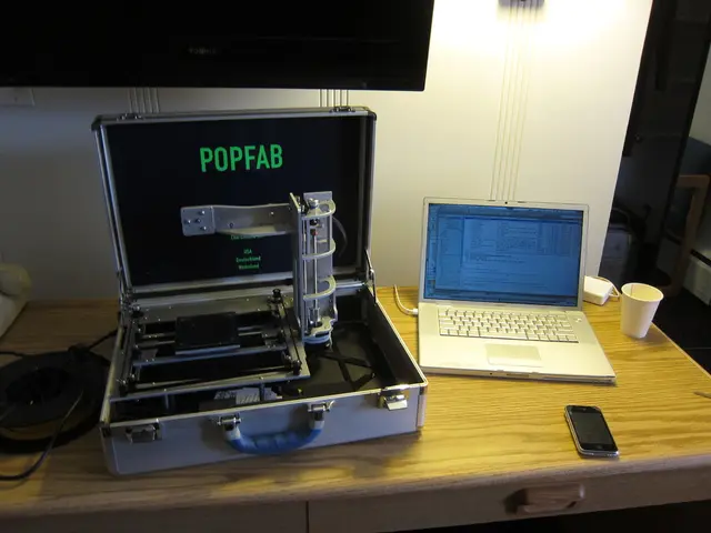 In the image there is a laptop, a mobile phone, a cup and other objects kept on a wooden table and...