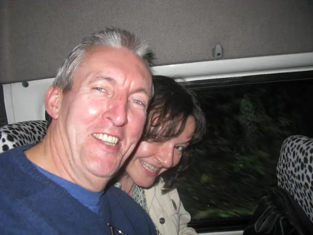 In this picture there is a interior of a vehicle where there is a couple sitting and smiling and...