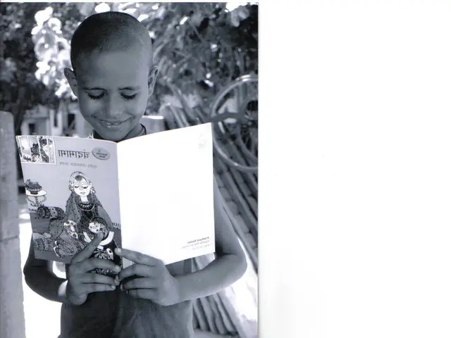 It is a black and white image, there is a boy standing in the foreground and holding a book and the...