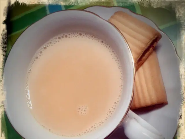 In this image we can see a saucer on which we can see some biscuits and a cup of tea.